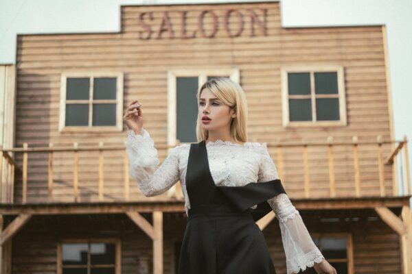 a beautiful woman in a dress in front of a saloon