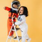 positive diverse children in astronaut costumes in studio