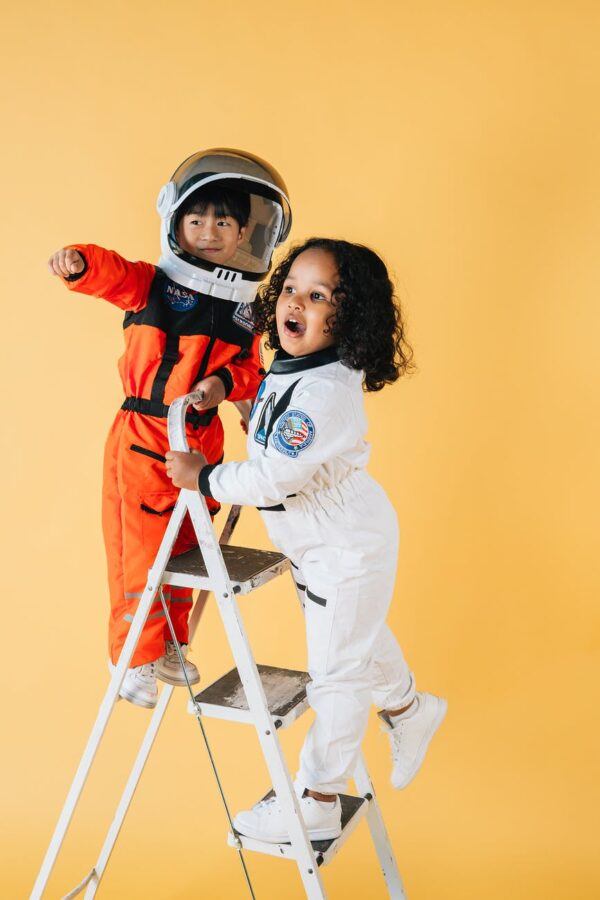 positive diverse children in astronaut costumes in studio