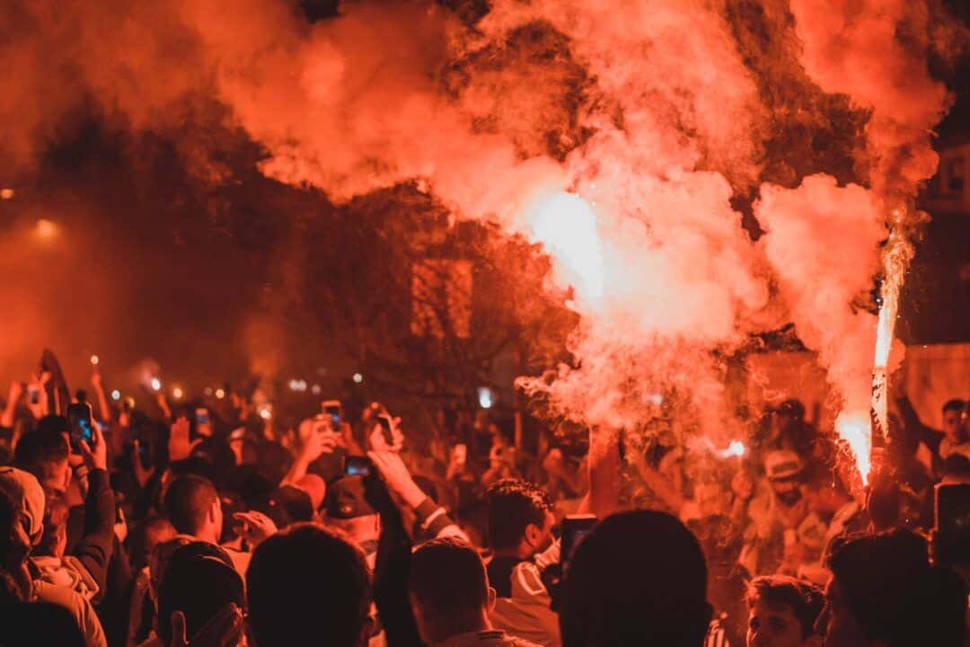 anonymous people standing on street among smoke during protests at night