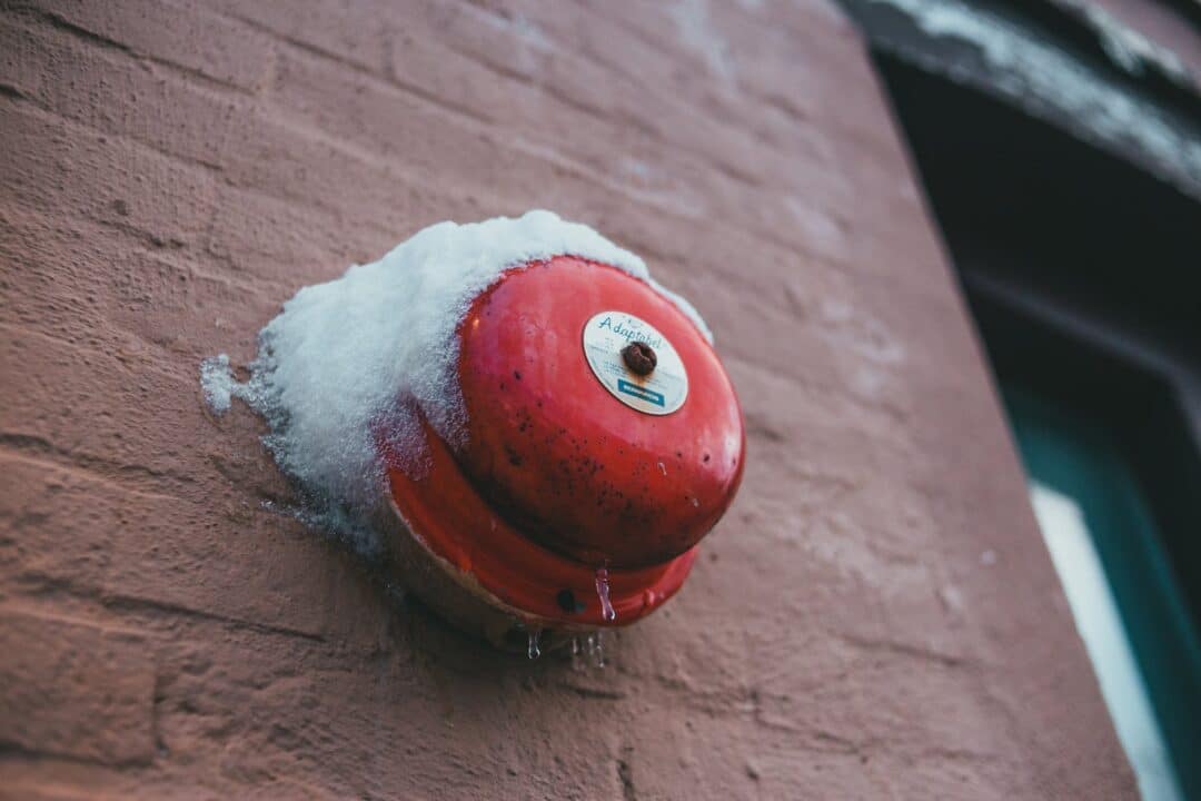 fire alarm button on brick wall of building in winter