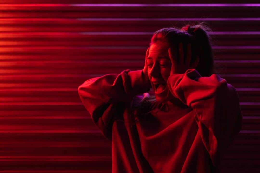 shouting woman with hands on head in dim red light