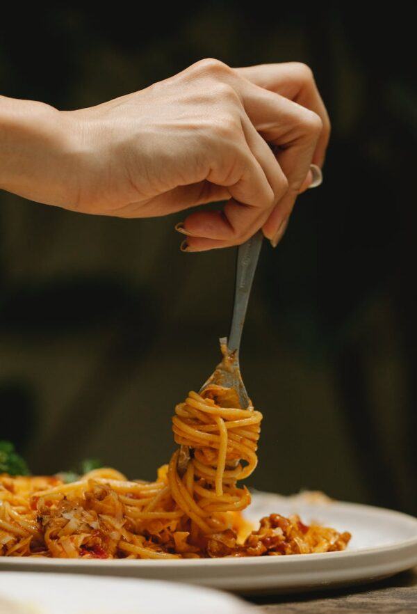 crop woman rolling spaghetti on fork during dinner in restaurant