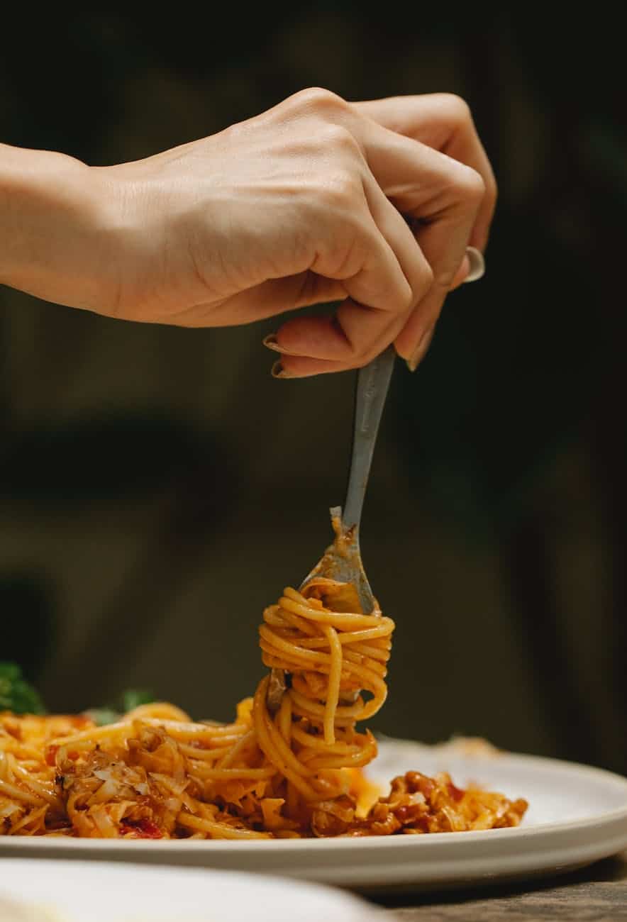 crop woman rolling spaghetti on fork during dinner in restaurant