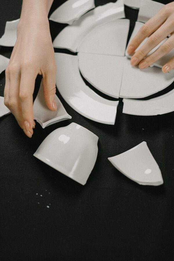 a close up on a female like hands assembling broken white plate