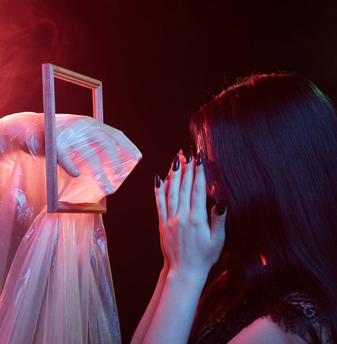 a hand wrapped with plastic reaching for a scared woman