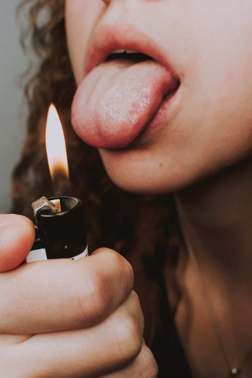 crop woman with lighter and tongue out