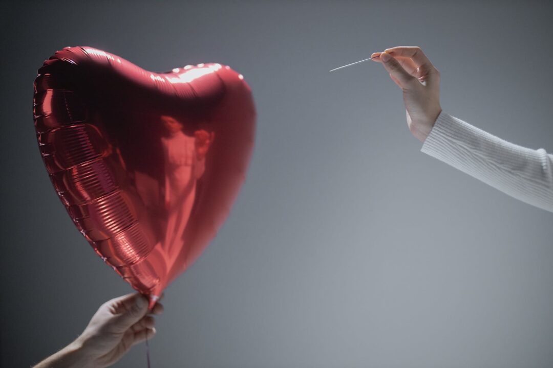 person holding red heart balloon