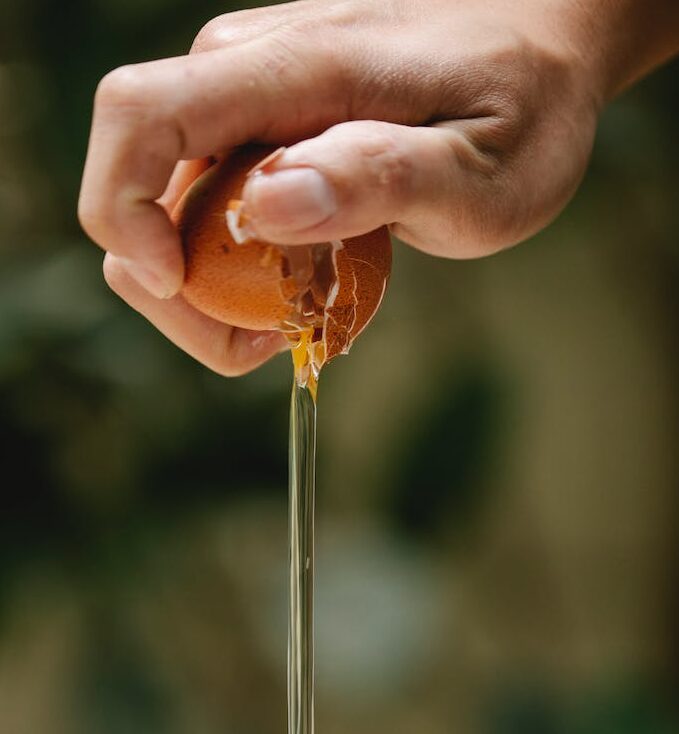 woman pouring white from cracked chicken egg