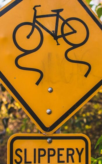 yellow and black slippery when wet road sign board